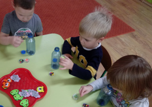 Dzieci wykonują grzechotki z butelek i koralików